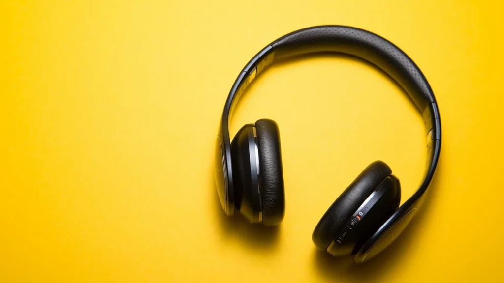 Black over-ear headphones on a yellow background illustrating music streaming