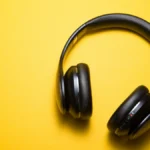 Black over-ear headphones on a yellow background illustrating music streaming