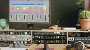 A home studio desk with an Ableton Live session on screen and outboard preamps and compressors below