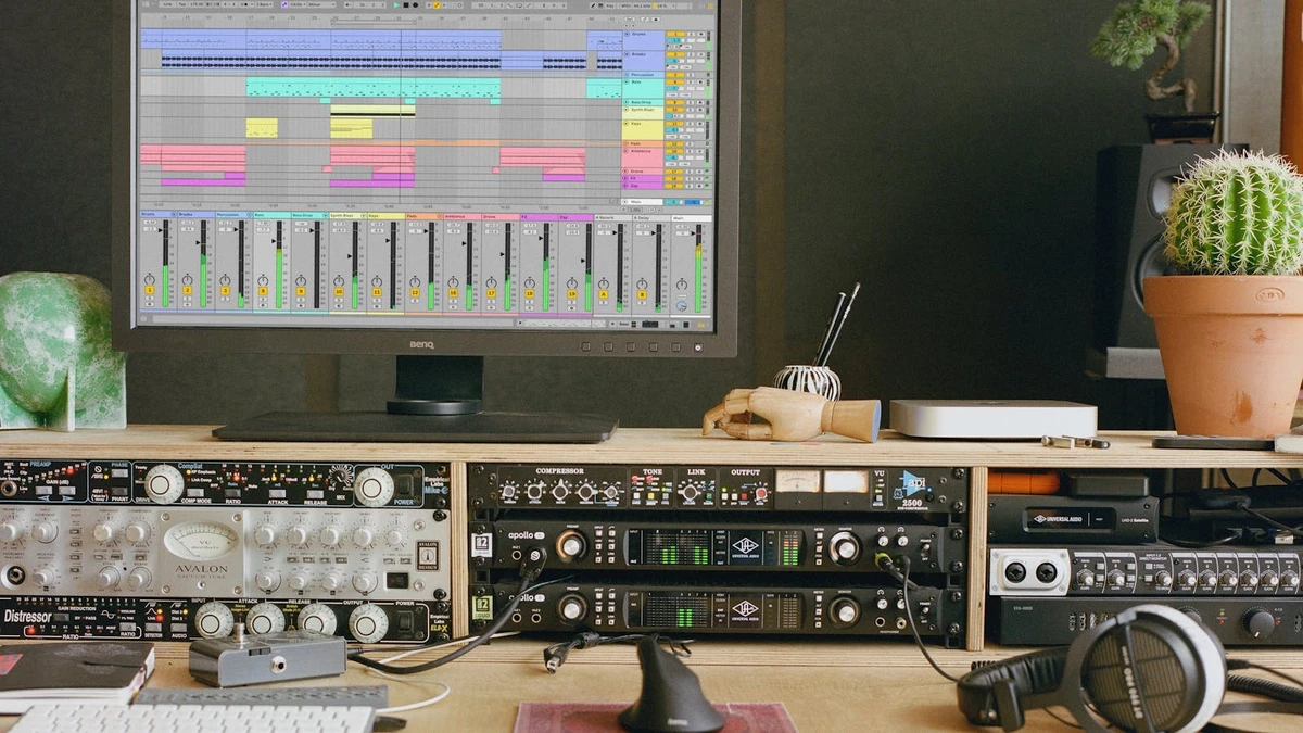 A home studio desk with an Ableton Live session on screen and outboard preamps and compressors below