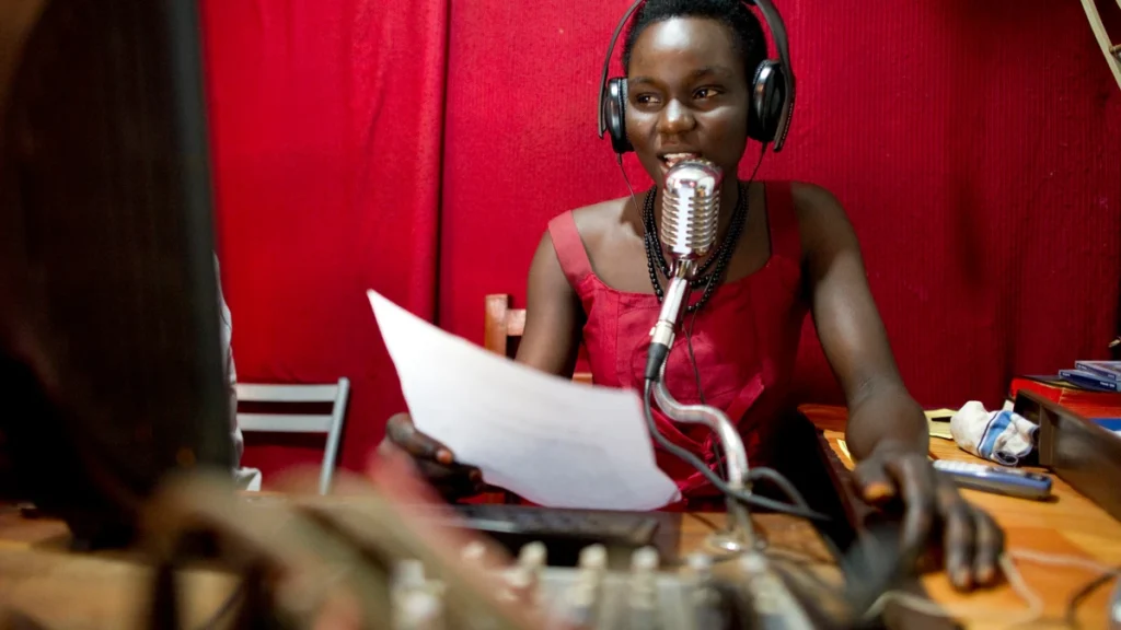 A radio presenter speaking into a microphone in a broadcast studio
