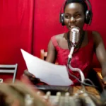 A radio presenter speaking into a microphone in a broadcast studio